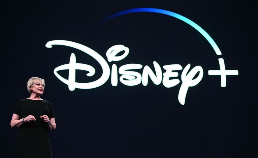 Photo of woman standing in front of Disney+ logo