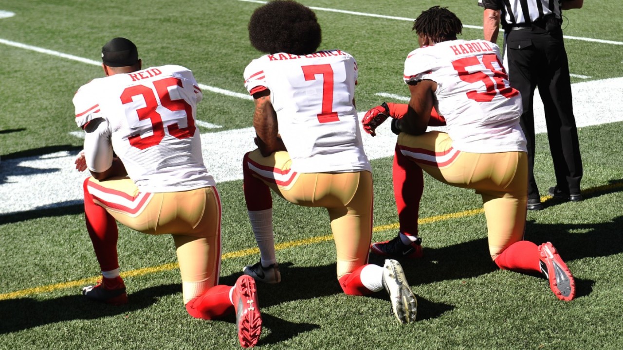 Colin Kaepernick and other football players kneel during the National Anthem