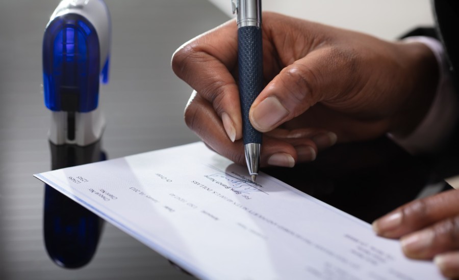 a black man signs a check