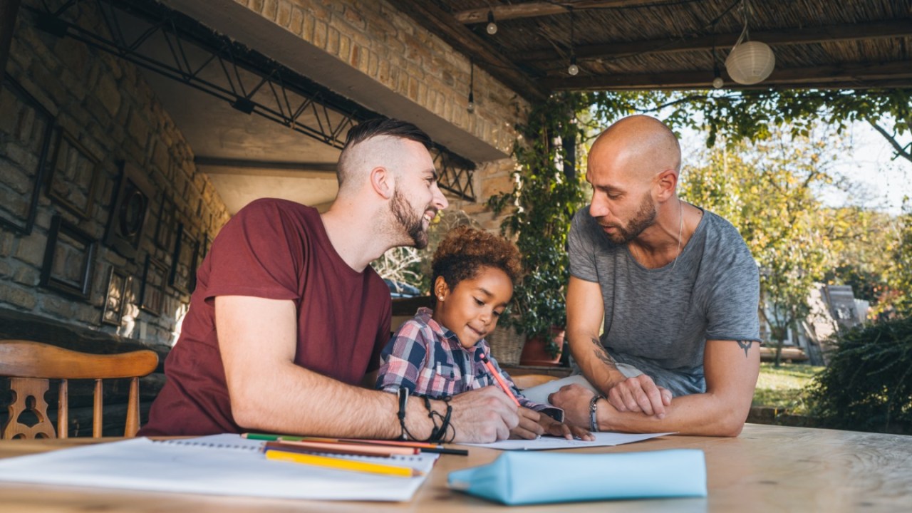 A gay couple sits with their child at a table.