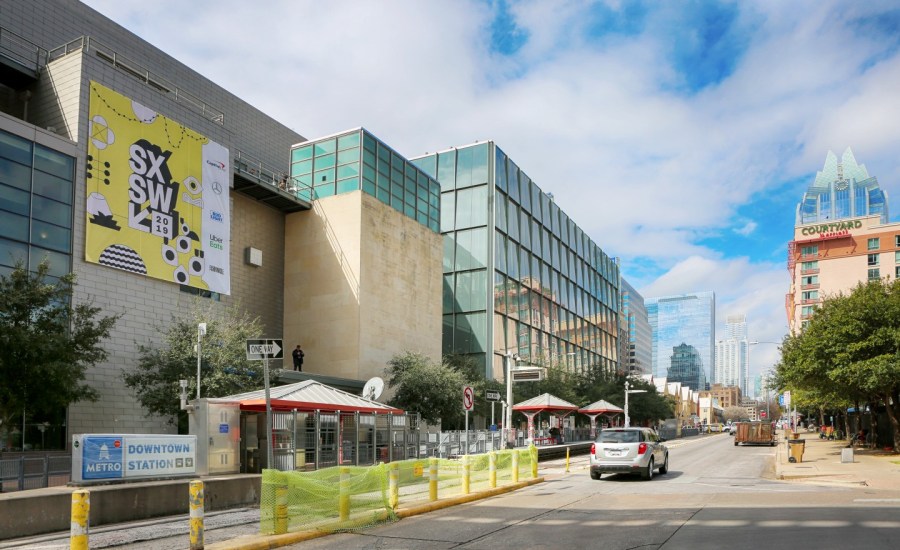 A view of downtown Austin, Texas, during the SXSW 2018 festival, which is advertised on a banner near a lane blocked for festival traffic.