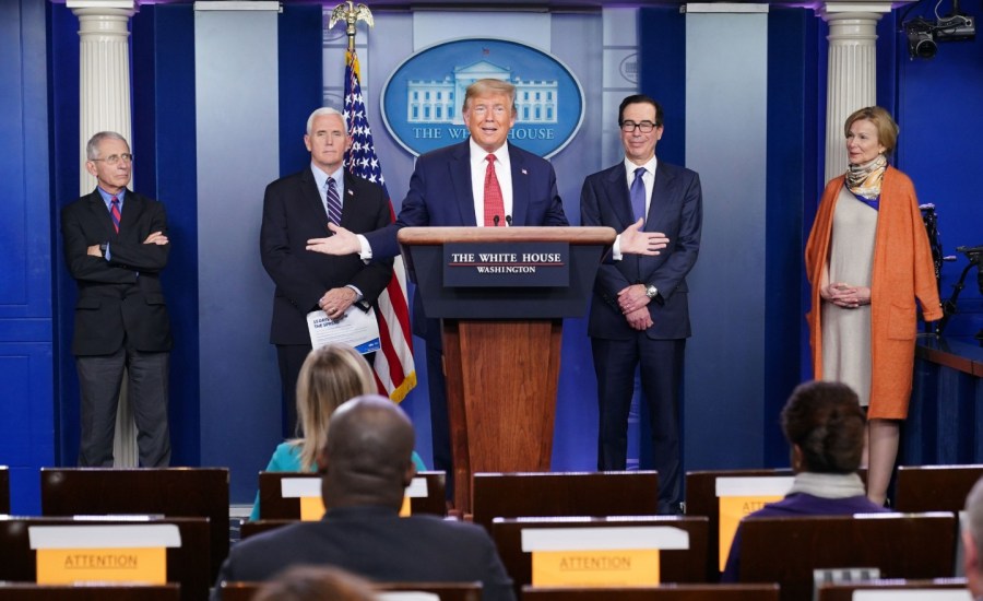 dr. deborax birx (right) in an orange dress with a scarf on the stage at the white house press room with (from left to right) dr. anthony fauci, vice president pence, president donald trump and secretary steven mnuchin