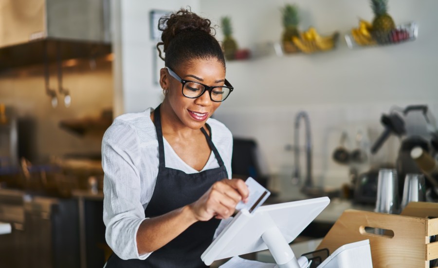 a black woman runs a credit card at the front of a store