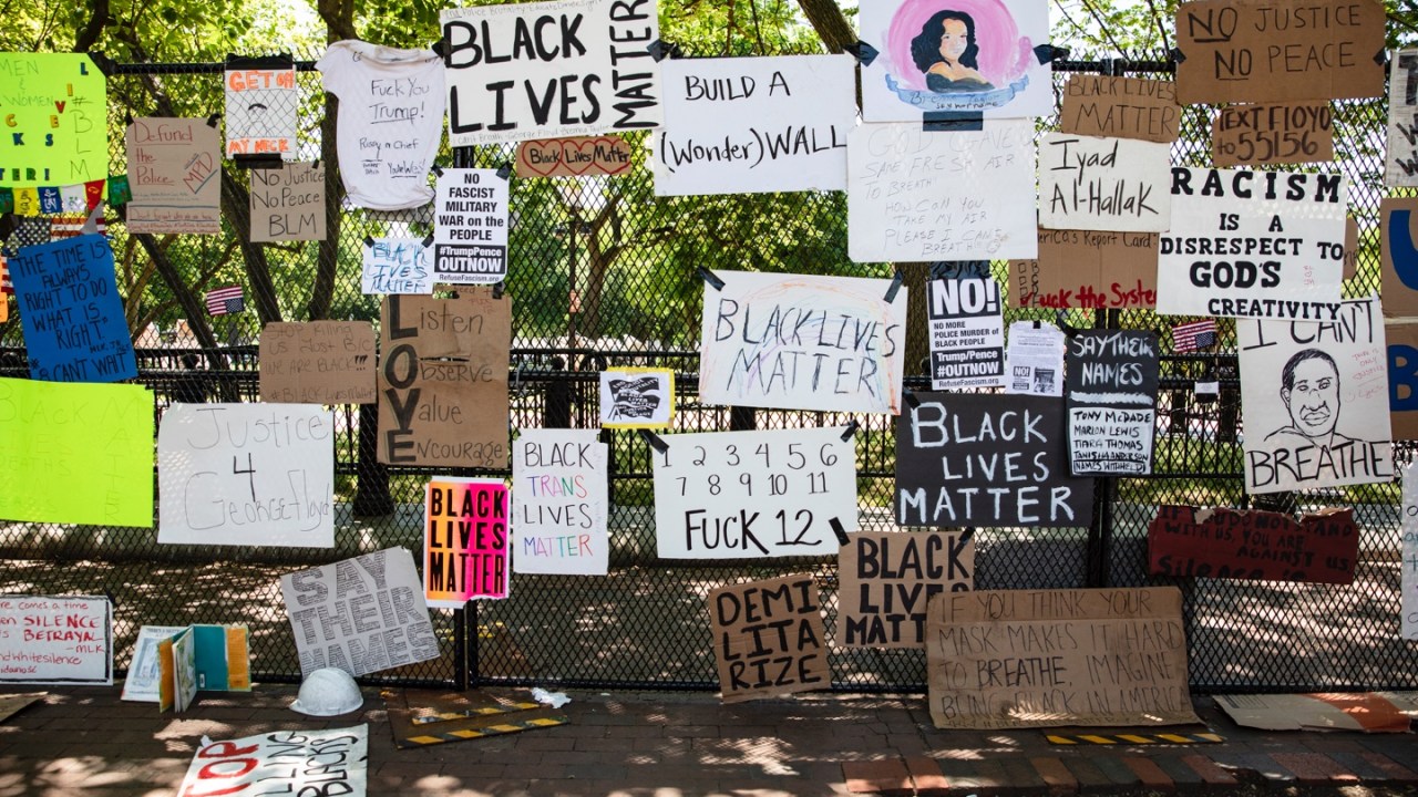 signs cover a fence in front of the White House