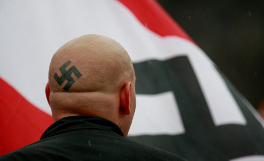 neo nazi with swastika tattoo on head and flag