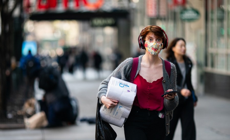 woman wearing a face mask carrying toilet paper