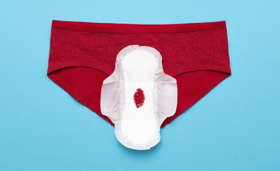 a menstruation pad with blood on it on red underwear