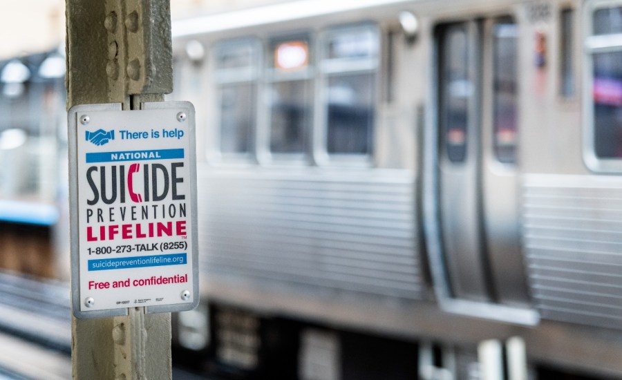 sign for suicide prevention hotline phone number at a train platform