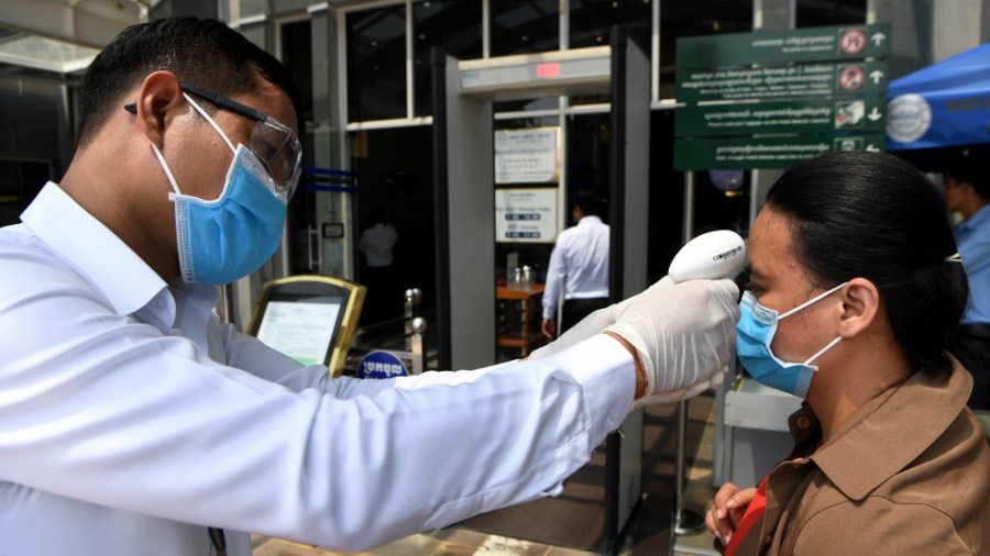 A health professional checks a person's temperature in Cambodia