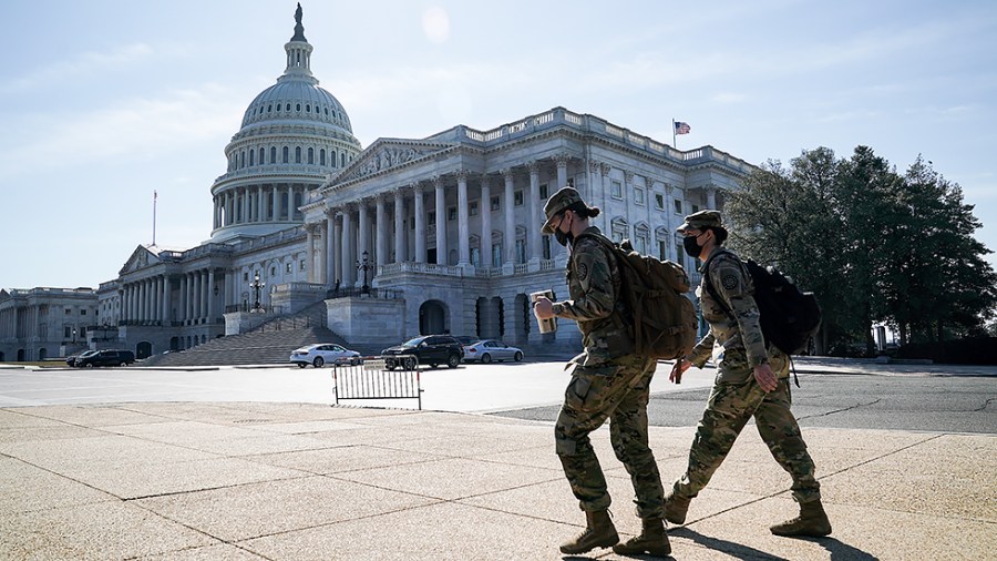 National Guardsmen walk past the Capitol