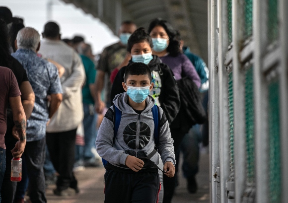 Deportees walk across a U.S.-Mexico border bridge from Texas into Mexico on February 25, 2021 in Matamoros, Mexico.