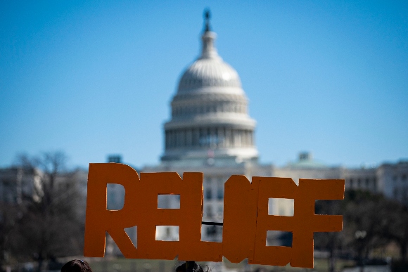 The U.S. Capitol is seen behind a sign during a demonstration in support of COVID-19 relief, organized by Shutdown DC, on the National Mall, on February 25, 2021 in Washington, DC.