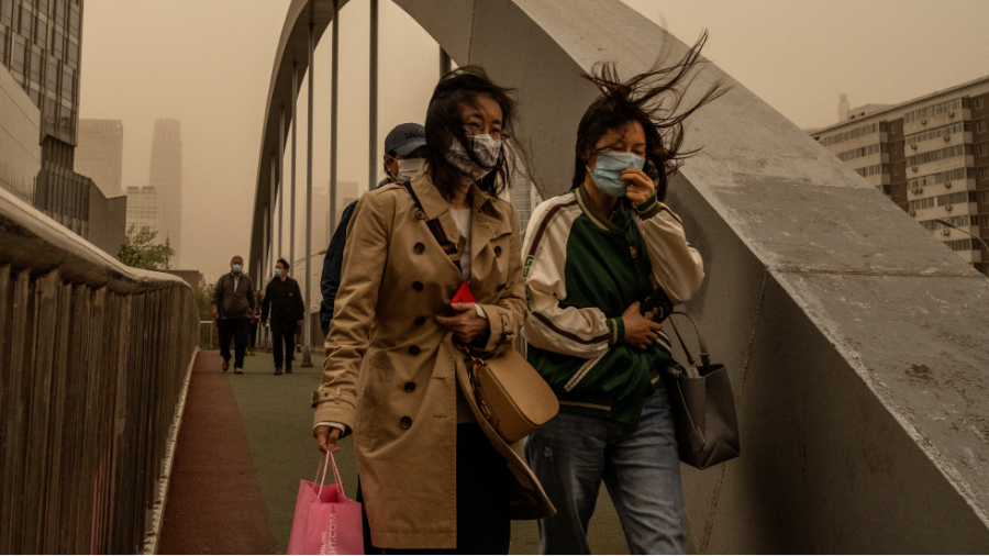 Women wear protective masks as they walk in heavy winds during a seasonal sandstorm on April 15, 2021 in Beijing, China