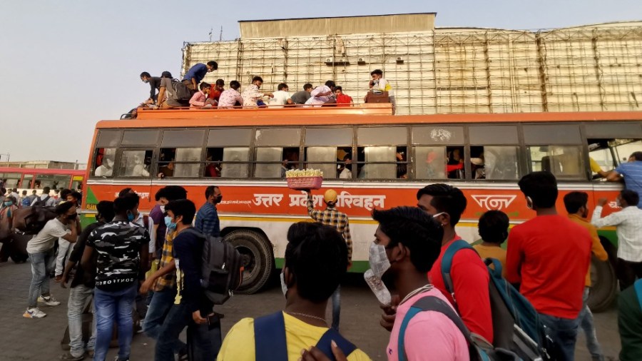 People crowd at a bus station to reach their native places hours before a week-long lockdown in India