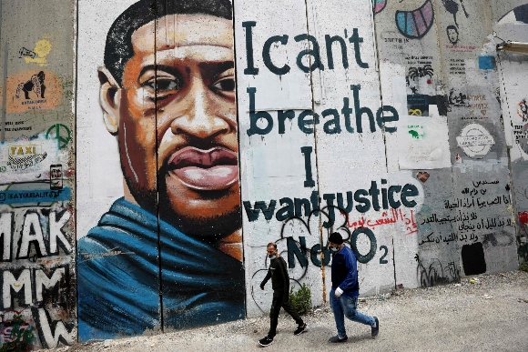 People walk past a mural showing the face of George Floyd