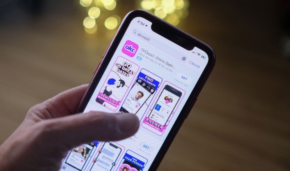 A person looking at the OkCupid dating app on a smartphone