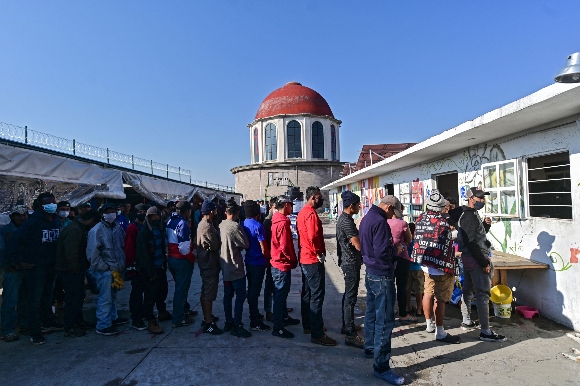 Central American migrants queue at the Sagrada Familia shelter