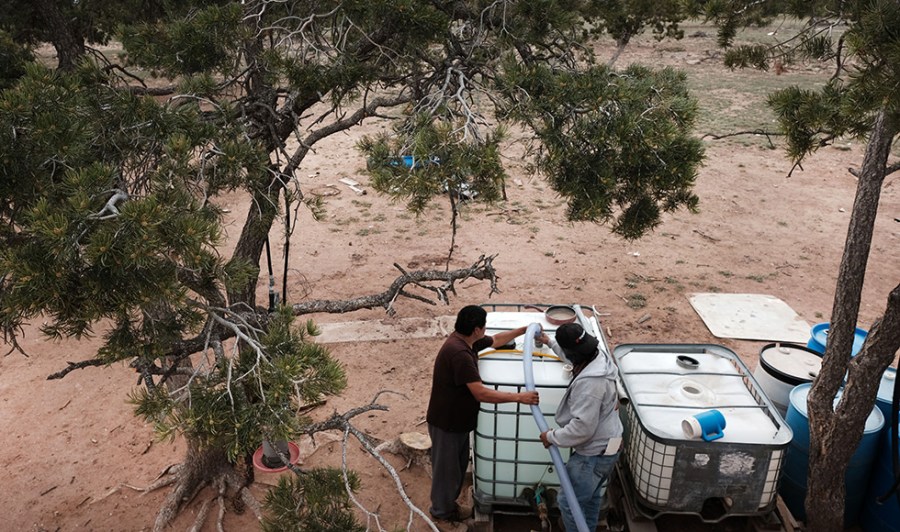 Cecil Joe (right), a Navajo Indian, fills a water tank of a fellow member of the Navajo Nation