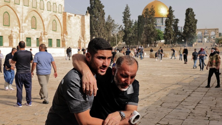 A Palestinianman helps a wounded fellow protester amid clashes with Israeli security forces at Jerusalem's Al-Aqsa mosque compound