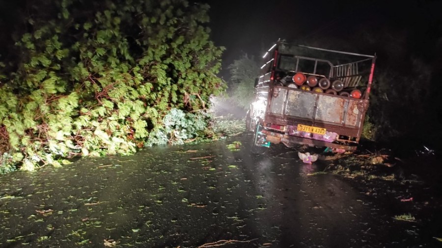 A truck loaded with oxygen cylinders is blocked by falling trees during the approach of Cyclone Tauktae, near Mahuva, India