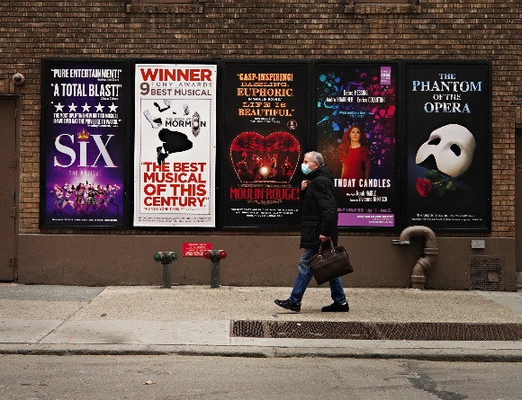 A person walks by Broadway posters near Times Square