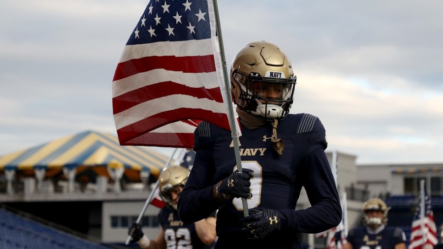 Cameron Kinley of the Navy Midshipmen carries an American flag as the team takes the field against the Tulsa Golden Hurricane in December 2020