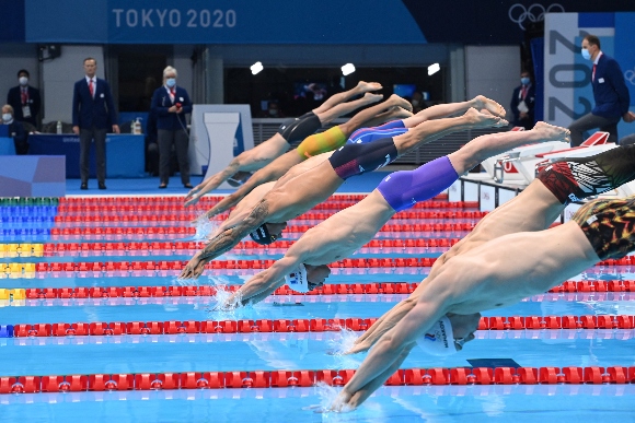 USA's Caeleb Dressel (C) and France's Maxime Grousset (3R) dive to compete in the final of the men's 4x100m freestyle relay swimming event during the Tokyo 2020 Olympic Games