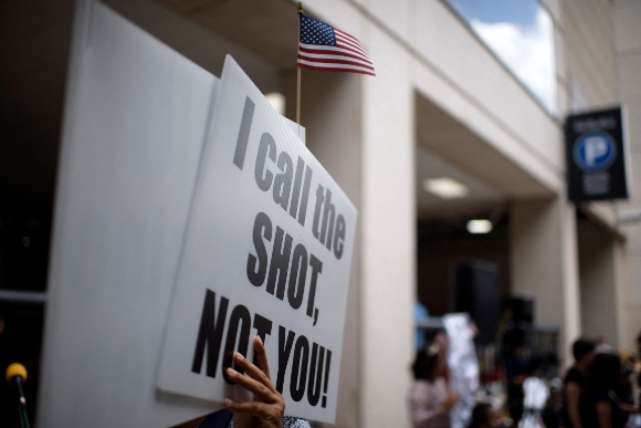 Anti-vaccine rally protesters hold signs outside of Houston Methodist Hospital