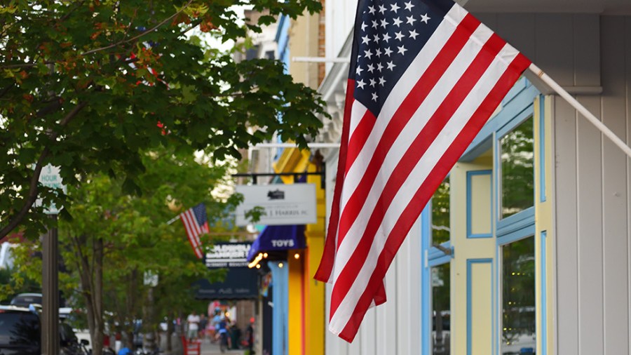 An American flag hangs in front of a storefront on a street