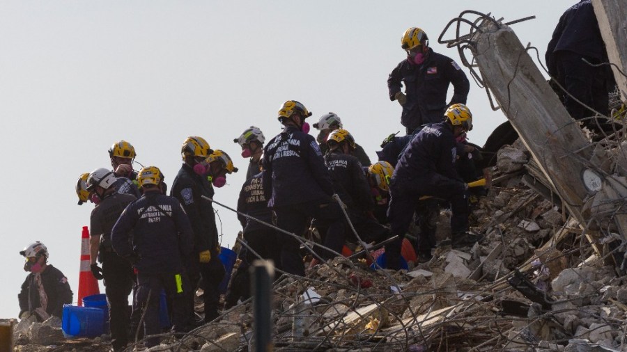 Rescue workers continue working on a pile of debris after the partially collapsed 12-story Champlain Towers South condo was taken down with a controlled demolition