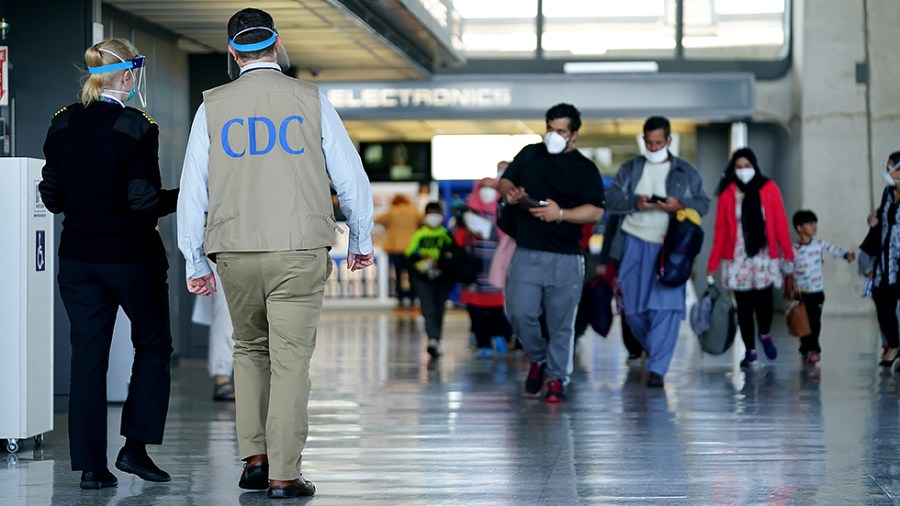 A Center for Disease Control official is seen as Afghans displaced from their homes due to the Taliban takeover arrive at Washington Dulles International Airport in Chantilly, Va. on Monday, August 30, 2021.