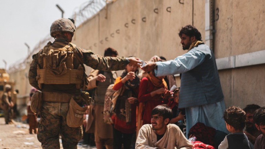 A Marine with the 24th Marine Expeditionary unit passes out water to evacuees at the Hamid Karzai International Airport in Kabul, Afghanistan