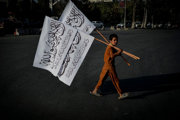 A boy carries Taliban flags to sell in the Karte Mamorin area of Kabul