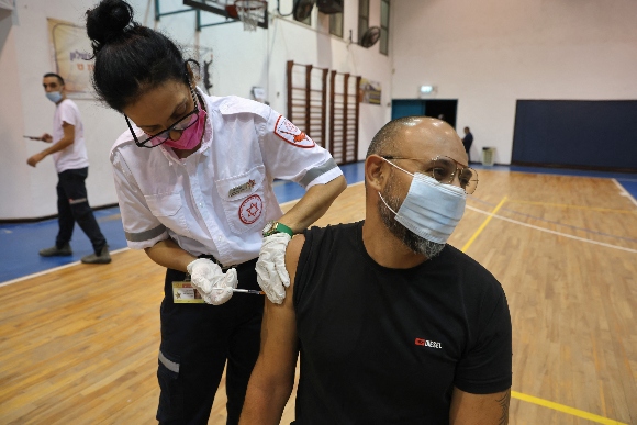 A paramedic with Israel's Magen David Adom medical service administers the third shot of the Pfizer-BioNTech Covid-19 vaccine