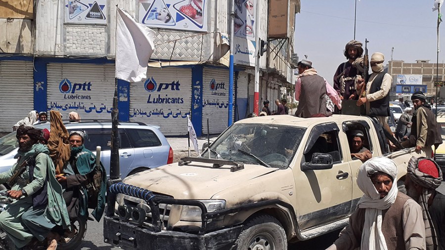 Taliban fighters drive an Afghan National Army (ANA) vehicle through a street