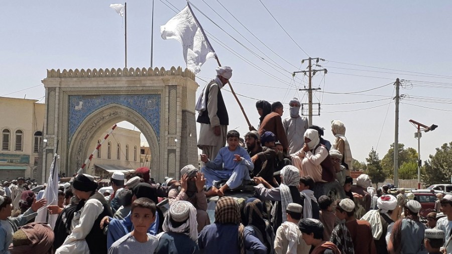 Taliban fighters stand on a vehicle along the roadside in Kandahar, Afghanistan