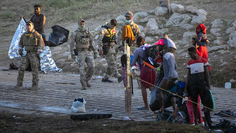 U.S. Border Patrol agents look on after Haitian immigrant families crossed the Rio Grande