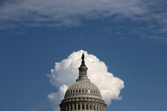 A cloud rises behind the U.S. Capitol building