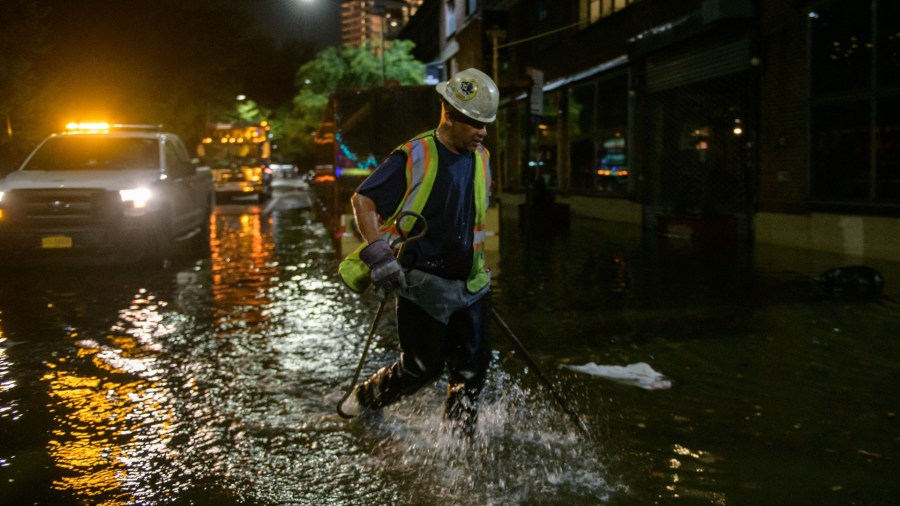 A worker wades through flood water in New York City