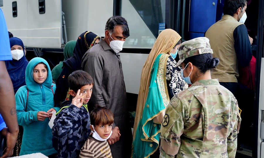 Adult and children Afghan refugees board a bus