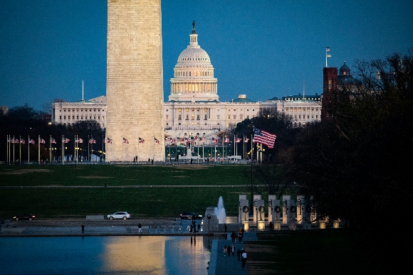 People walk along the Reflecting Pool on the National Mall, near the U.S. Capitol and Washington Monument