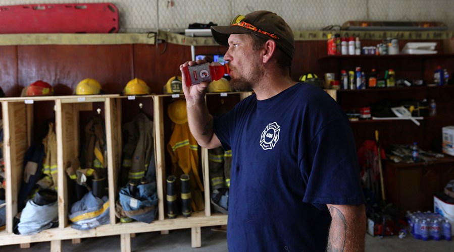 A volunteer firefighter stands in an aging fire station