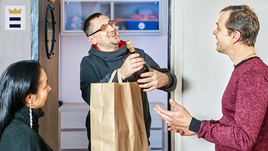 man giving a bottle of champagne to host