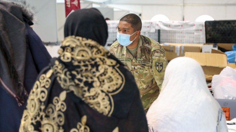 Army 1st Lt. Sanjay Gauntlette hands out essential items to U.S.-affiliated Afghans prior to their departure from Camp Liya, Kosovo