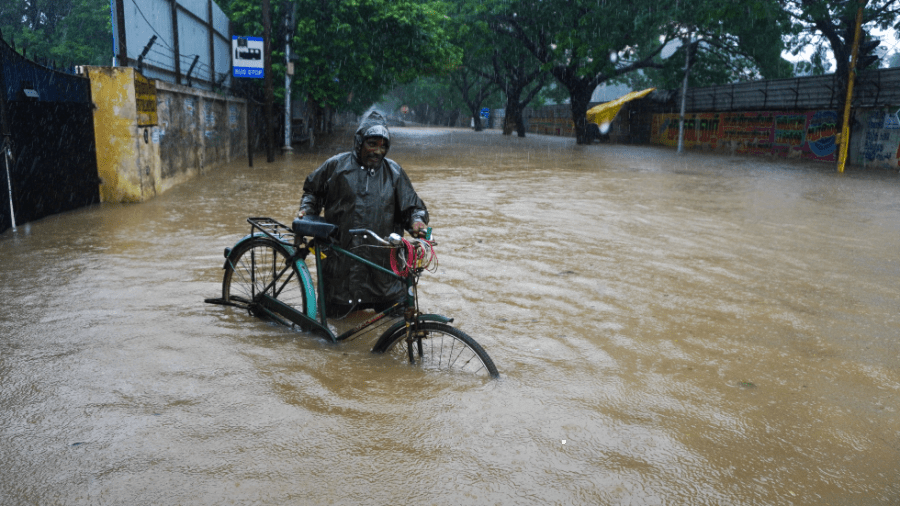 A man pushes his cycle past a flooded street in Chennai, in the southern Indian state of Tamil Nadu