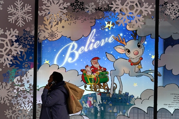 A shopper carries bags over her shoulder while passing a holiday display window outside a Macy's store 