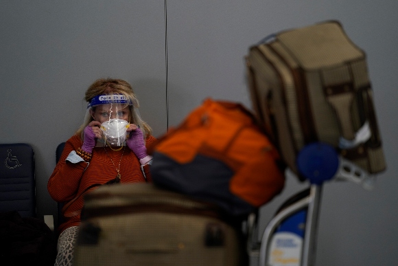 A traveler adjusts her mask while waiting to check in for her flight at the Los Angeles International Airport