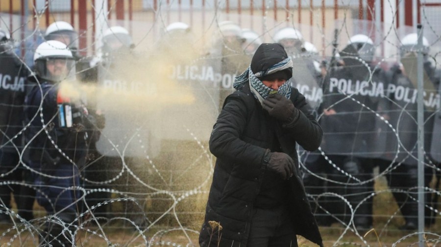 Polish serviceman sprays tear gas during clashes between migrants and Polish border guards