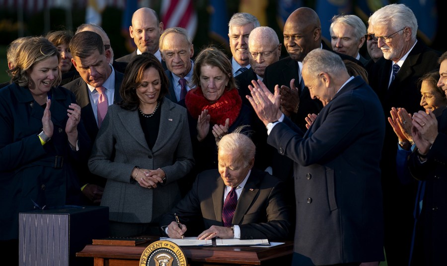 President Biden signs the Infrastructure Investment and Jobs Act as other lawmakers celebrate around him