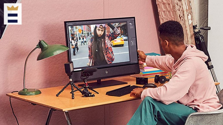 Person sits at computer desk, adjusting computer monitor.